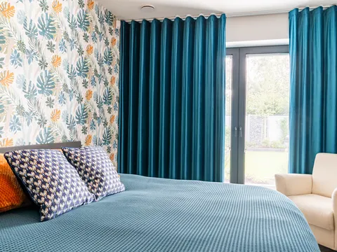 Petrolblauwe velours overgordijnen in de slaapkamer