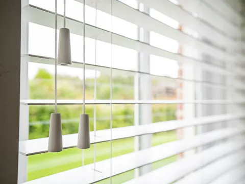 Een witte houten jaloezie met houten trekeikels