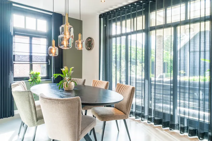 Donkere inbetweens rond de eettafel, met een vouwgordijn in het zijraam